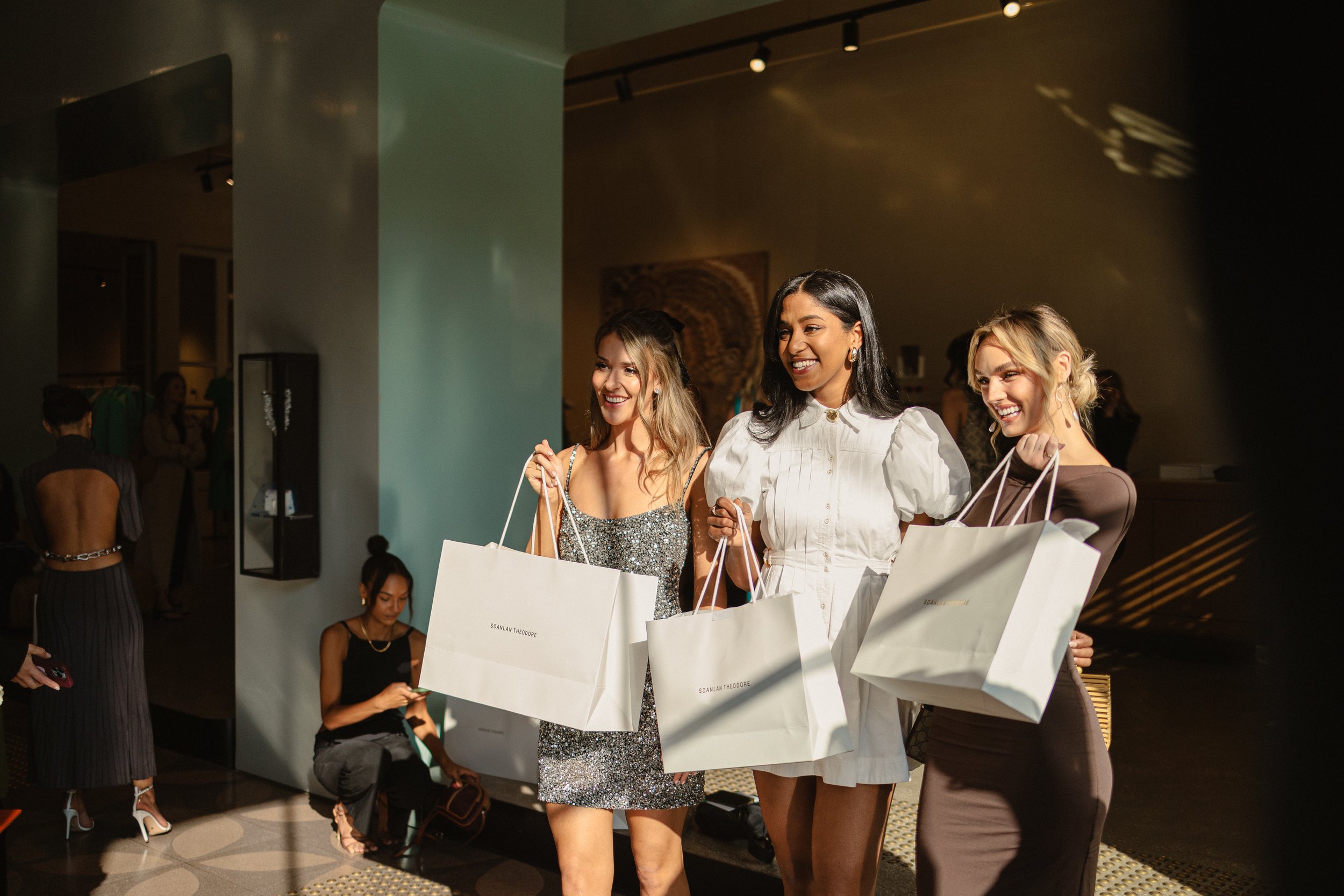 3 women holding shopping bags in boutique