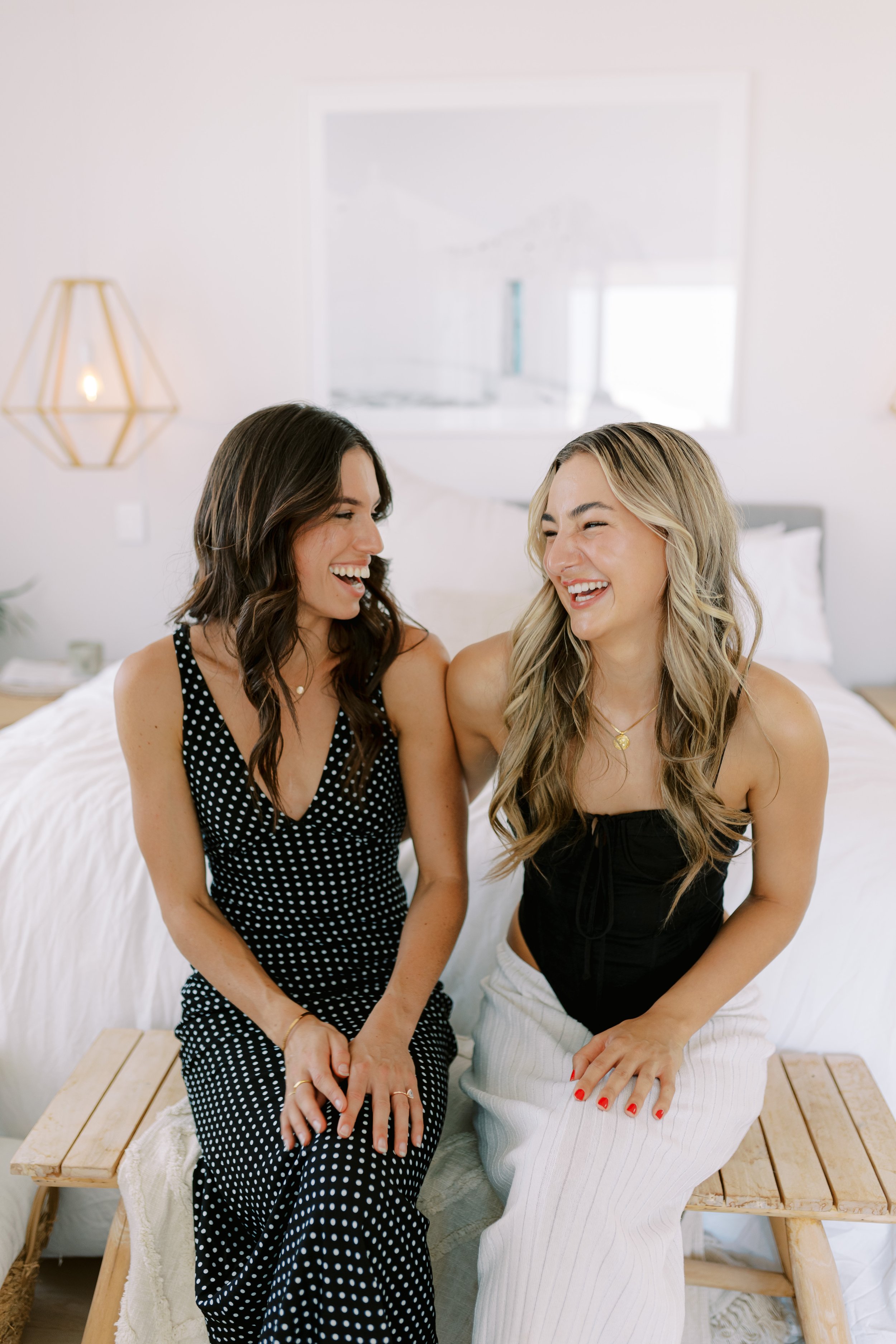 2 models posing on end of bed laughing