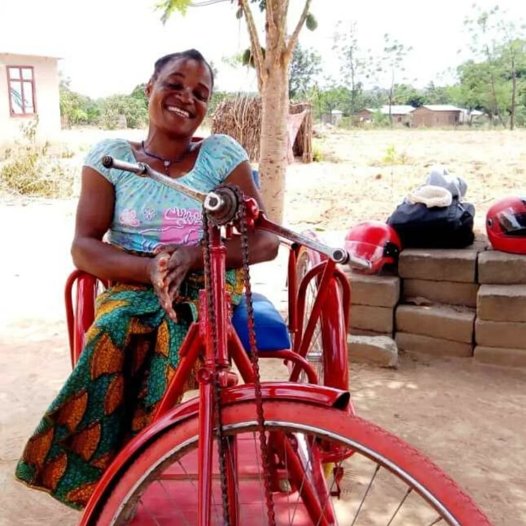 Woman using an adaptive tricycle through the Outreach Health disability programme in rural Tanzania