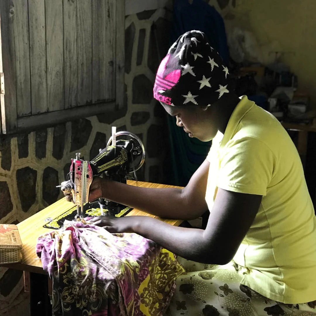 Young woman learning sewing and vocational skills as part of a community empowerment project in rural Tanzania