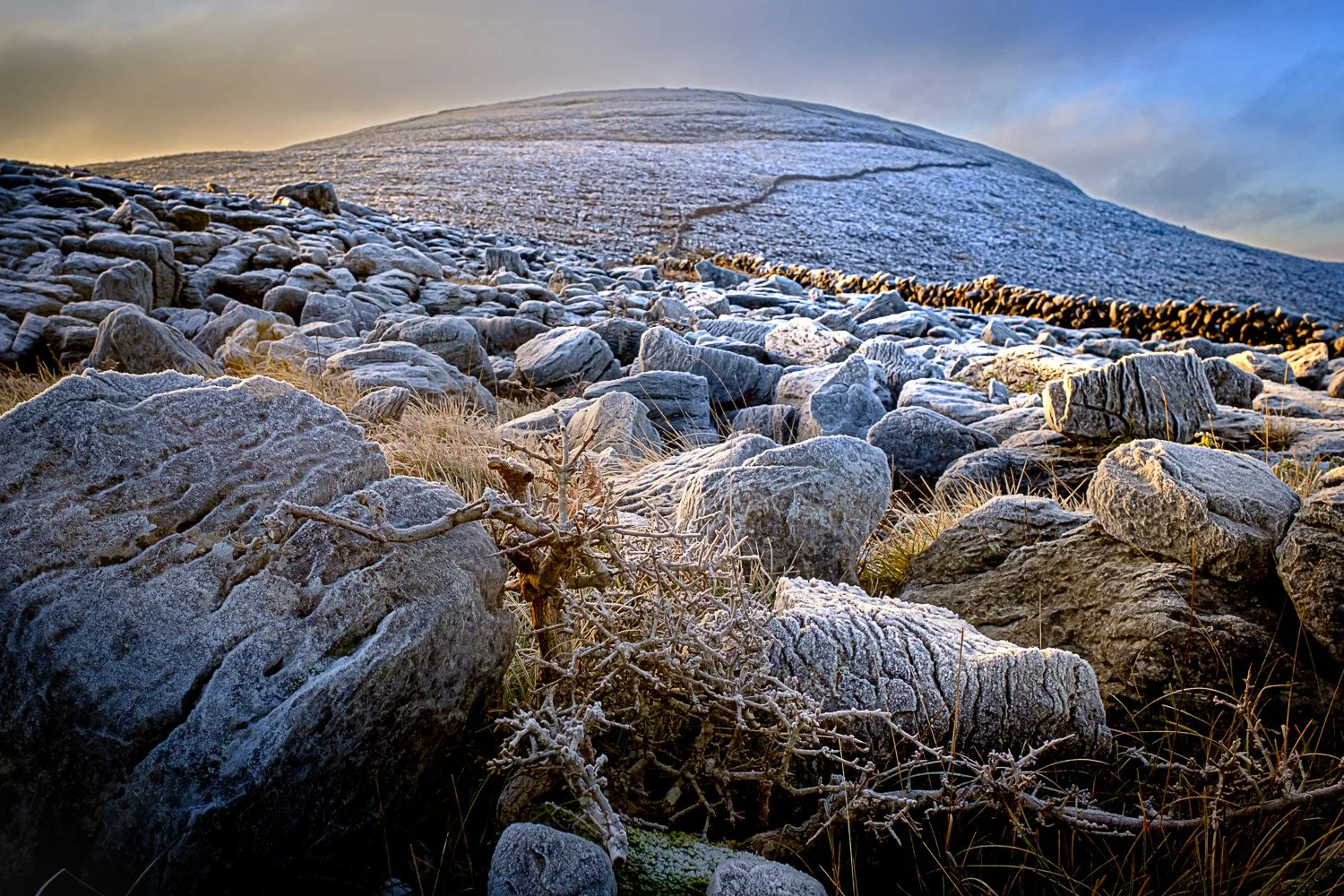 Slieve Oughtmama covered in powdery snow beneath a blue winter sky, seen across from Abbey Hill in the Burren, Ireland