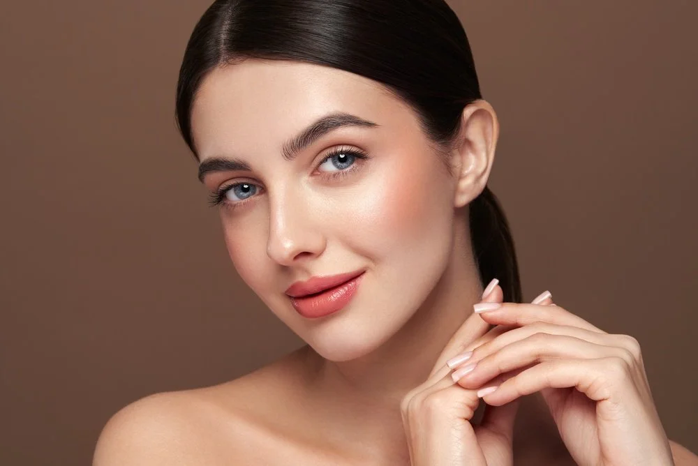 Woman with long curly lavender hair, wearing black top, looking down.