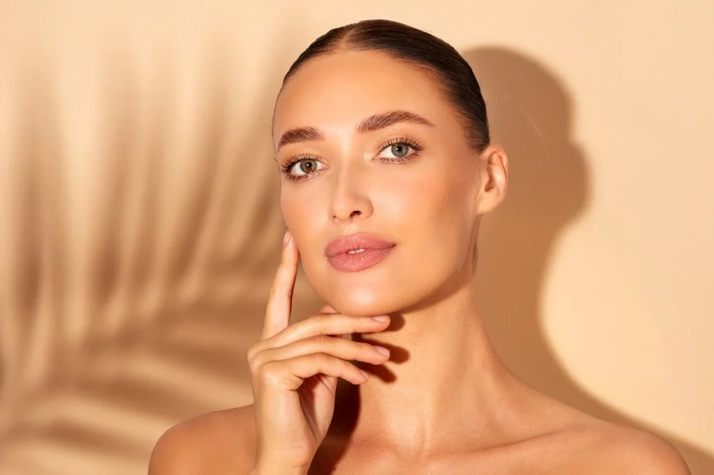 Person sitting on concrete steps wearing yellow floral high-heeled sandals beside blooming white hydrangeas.