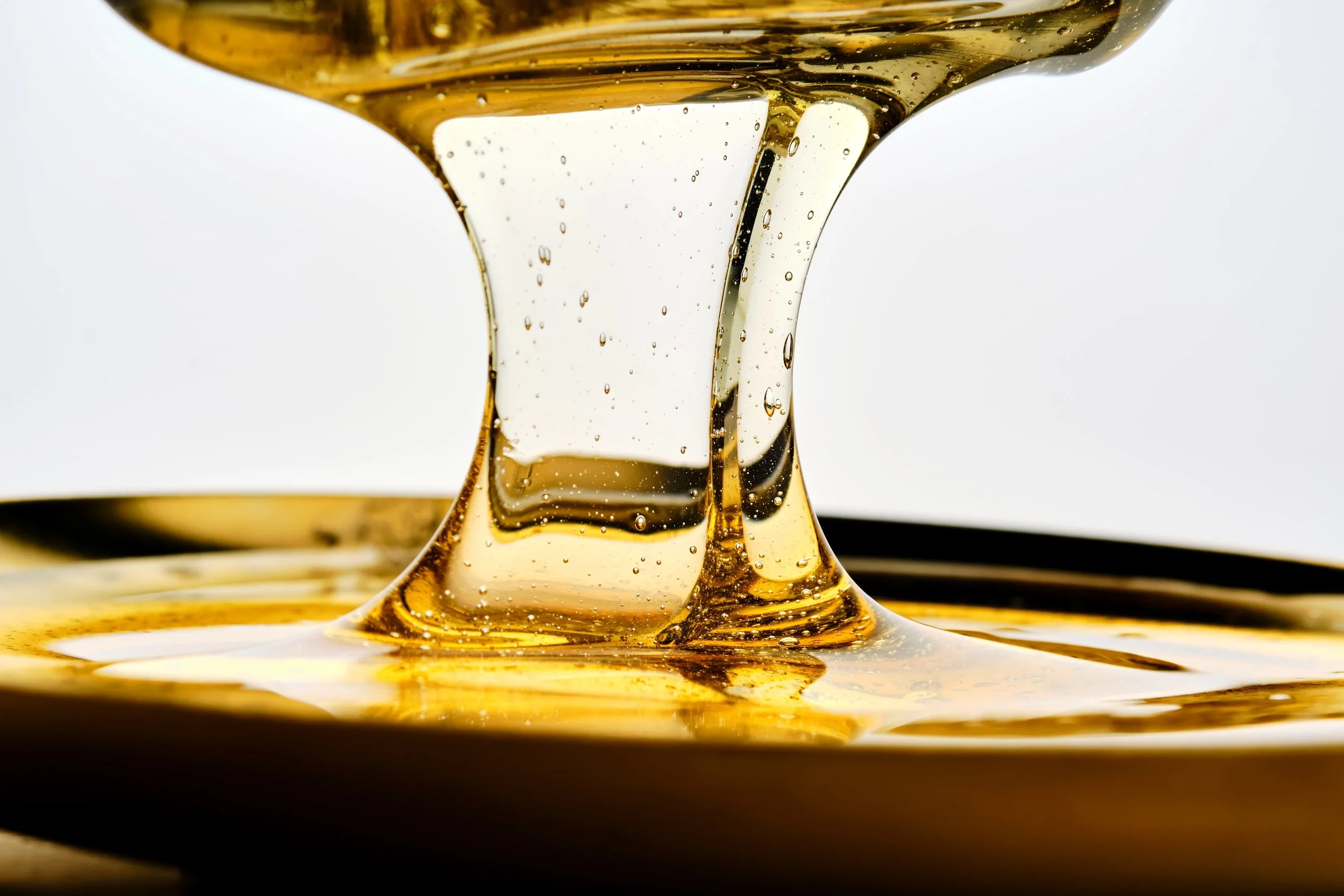 Close-up of honey being poured from a spoon, showcasing its golden color and viscous texture.