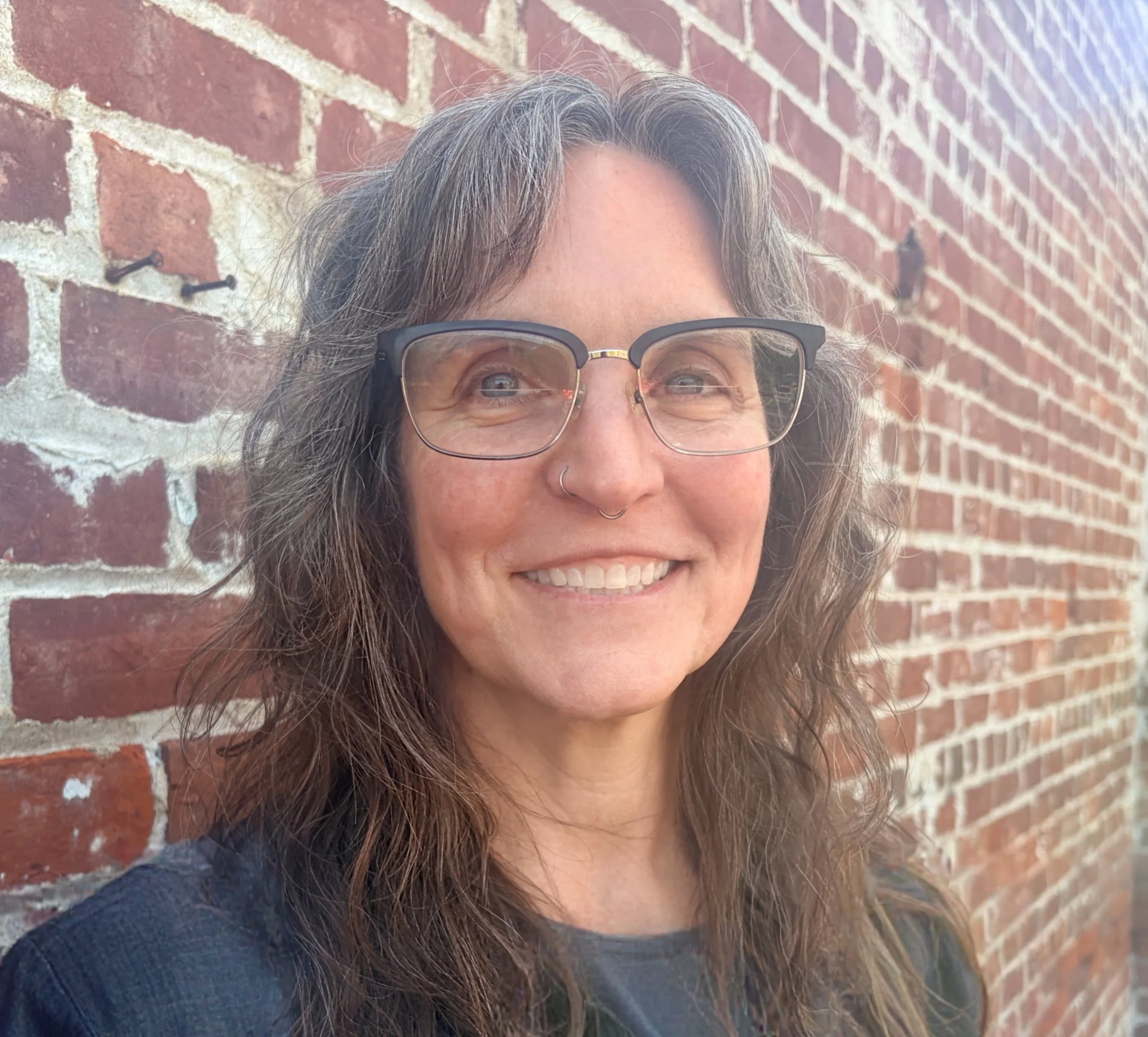 Image of Heather's face, with a brick wall background