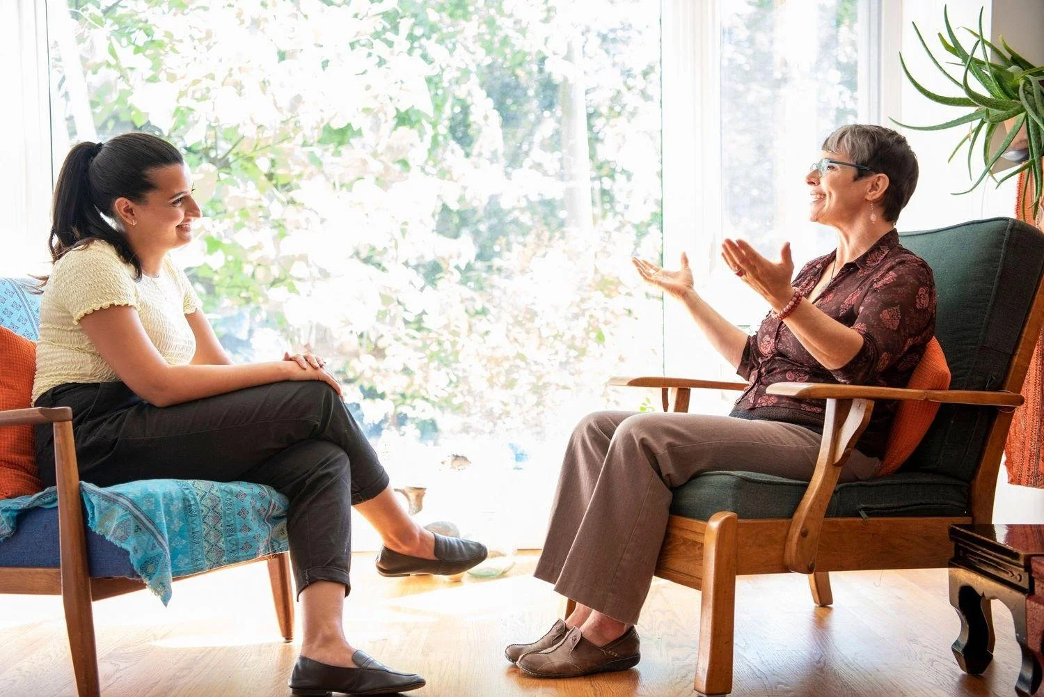 Photo of two women sitting in chairs facing one another talking. Wondering if you have to tell your therapist everything? Learn how EMDR therapy in Birmingham, AL can help you without requiring you to detail every traumatic experience.