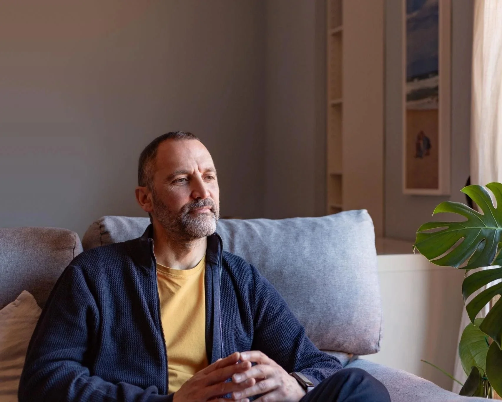 Photo of man sitting on couch looking contemplative. Are you ready to learn what to expect from EMDR therapy? Sparrow Counseling in Birmingham, AL is sharing 5 things to know before you begin.