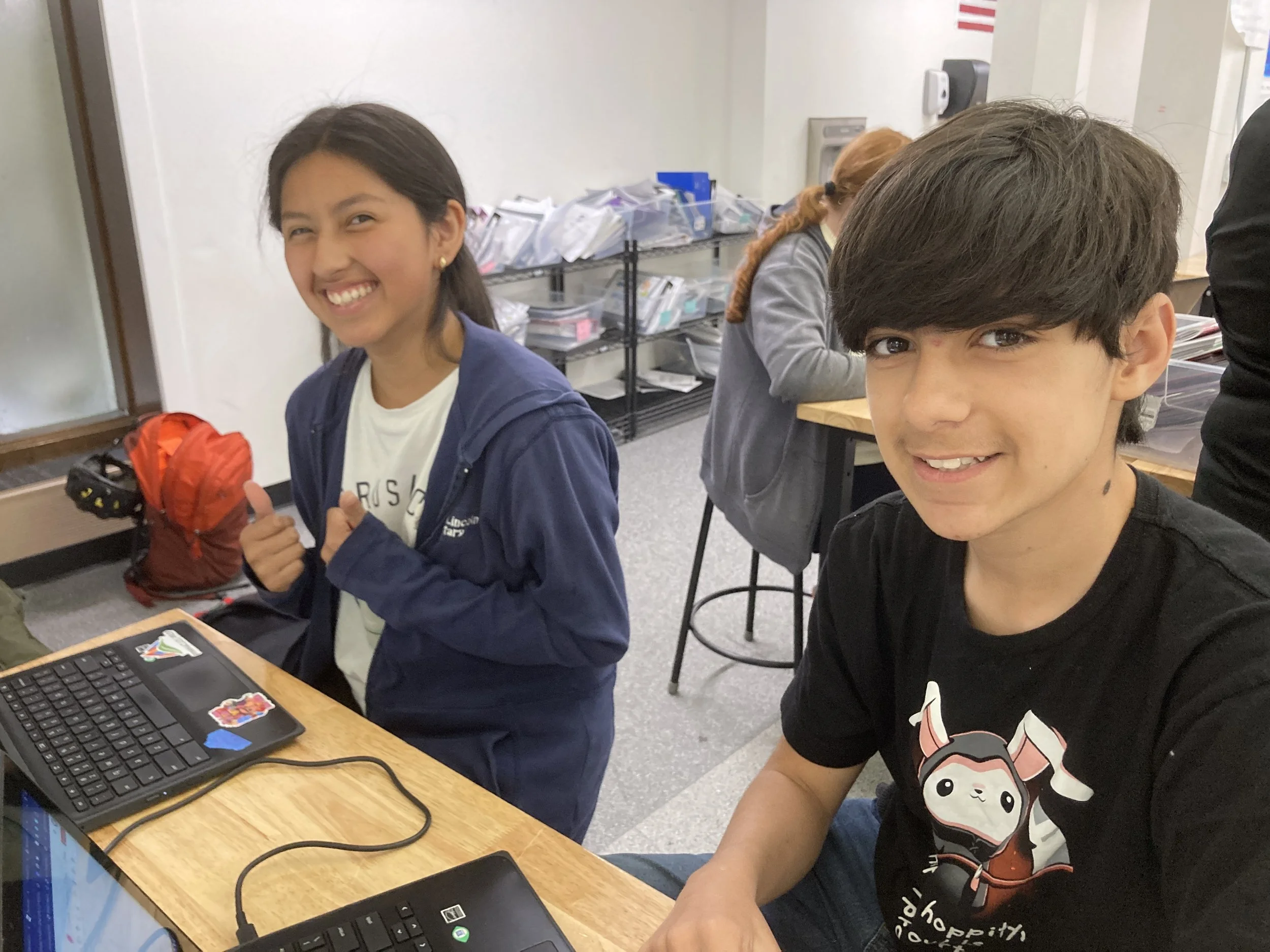 Scenic landscape of a mountain range with a lake in the foreground and grassy hills, under a cloudy sky.