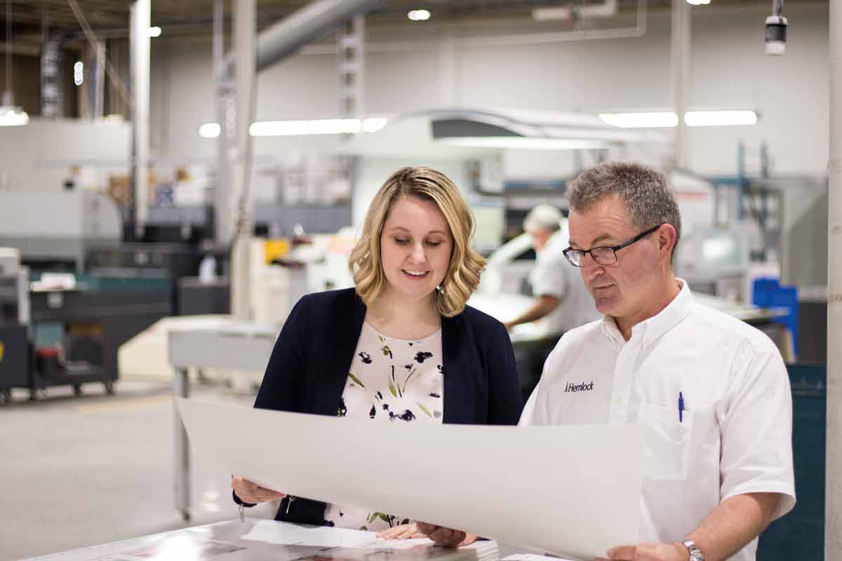 Colleen Moyles, marketing coordinator, and Jeff Cooper, production manager, review a printed sheet on the floor of Hemlock’s pressroom. SUPPLIED