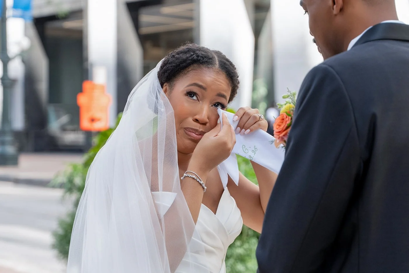 Bride wiping her tears with a custom handkerchief after her first look