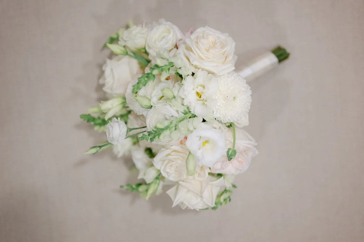 White wedding bouquet filled with roses, ranunculus, and lisianthus by Yanni Design Studio