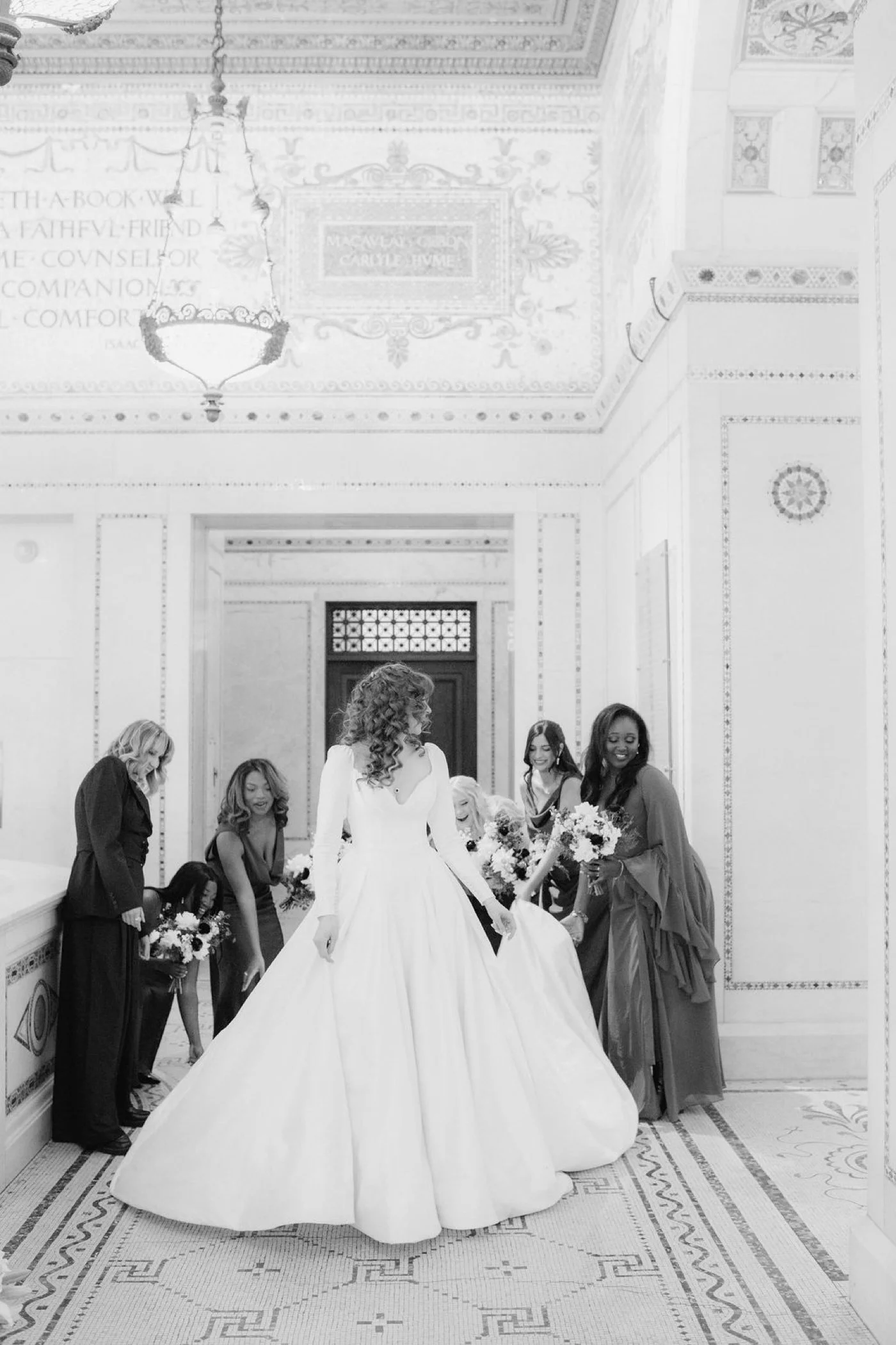 Bridesmaids lifting the hem of bride's wedding gown