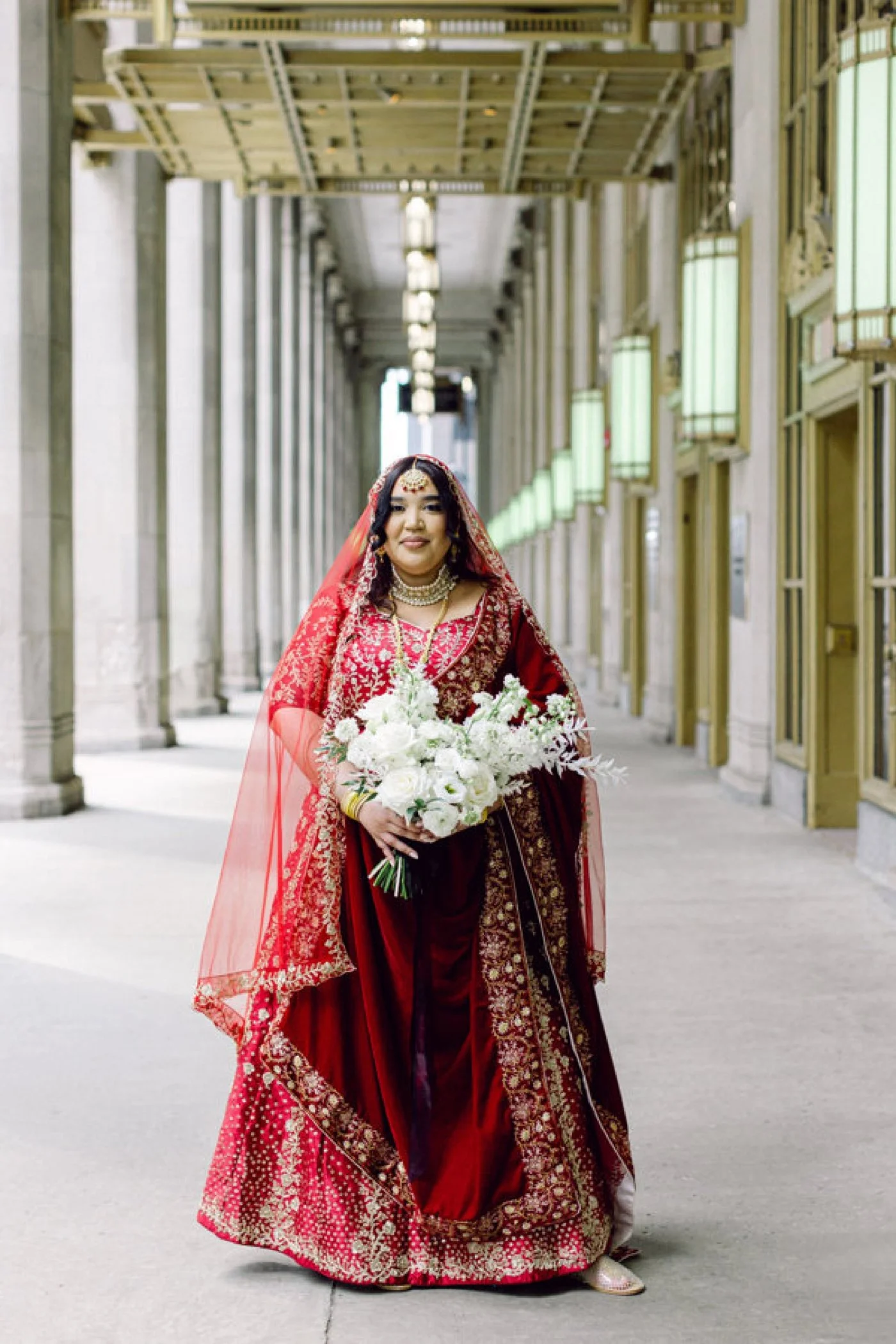 Indian bride wearing a red-and-gold saree and traditional gold jewelry for her Chicago wedding