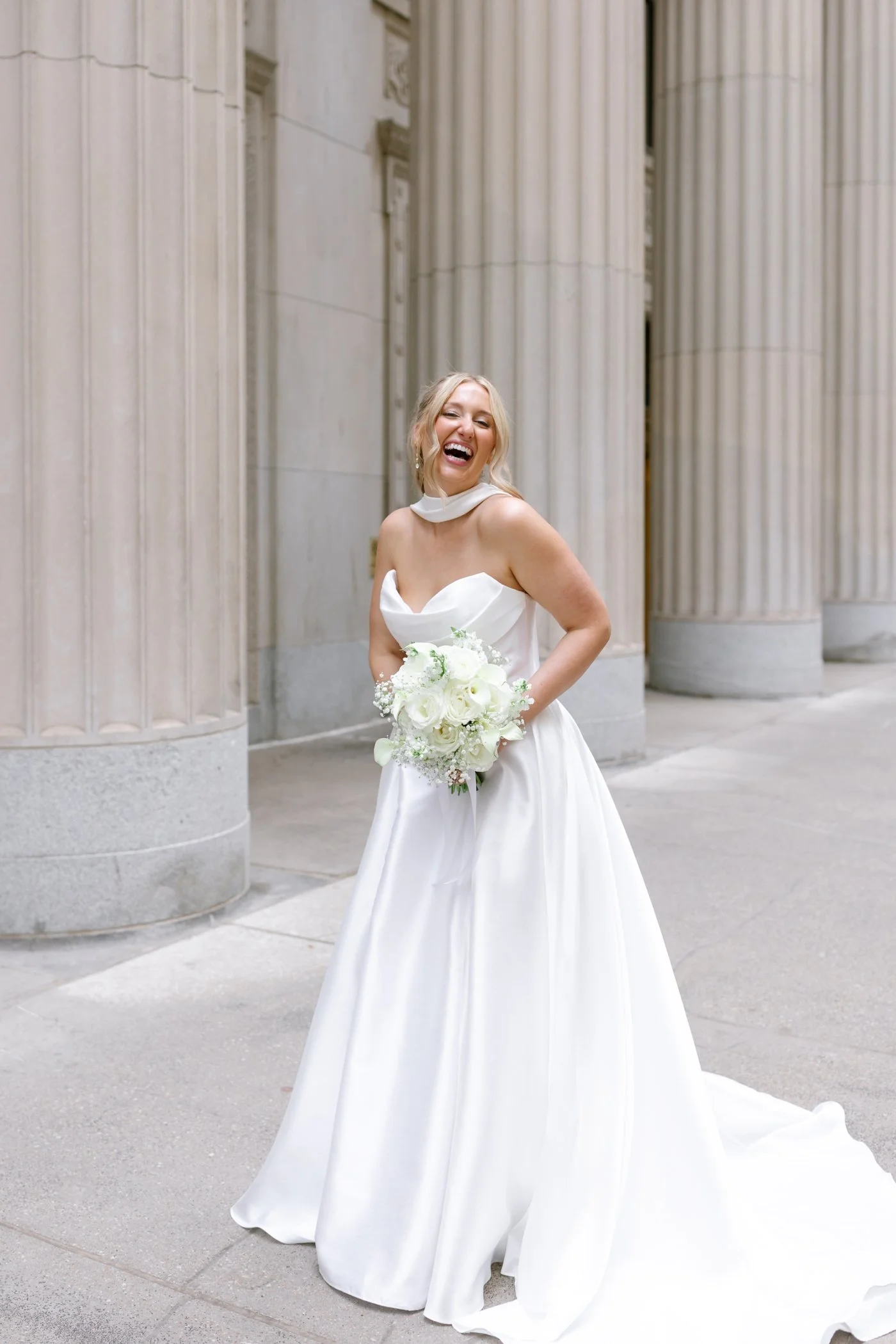 Bride wearing a strapless wedding dress with scarf and holding a white bouquet