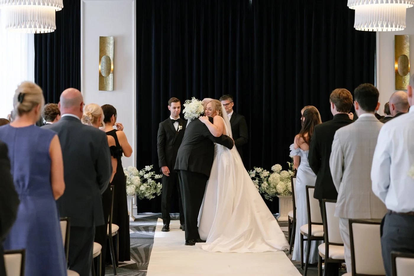Bride and father of the bride hugging after walking down the aisle