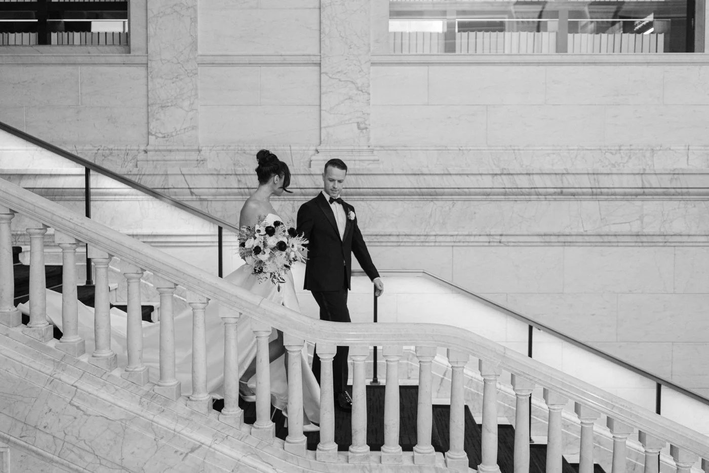 Groom leading bride down staircase, black and white portrait