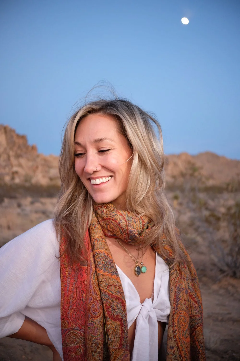 Astrologer Sarah Paasch laughing in the desert with the moon in the sky