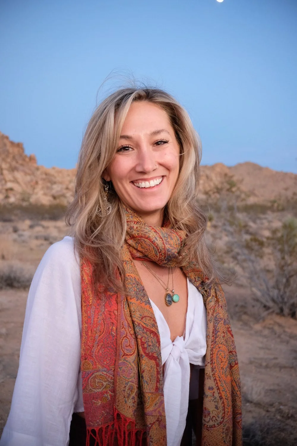 Astrology coach Sarah Paasch smiling in the desert under a clear blue sky