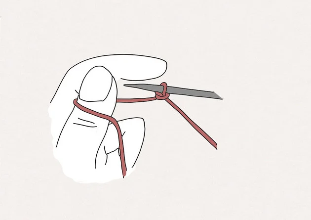 1. Commencez par réaliser un nœud coulant sur l'aiguille. Tenez ensuite votre aiguille et le fil de la pelote dans la main droite. Tenez l'autre brin du fil dans le creux de votre main gauche, puis enroulez le fil derrière votre pouce gauche.