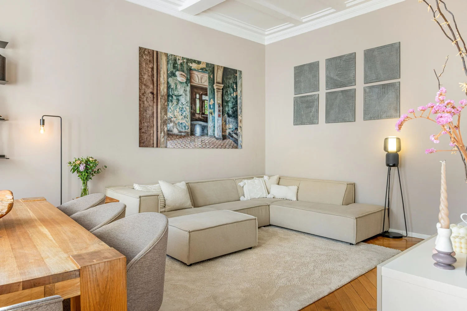 Neutral living room with a cream corner sofa, floor lamps, a rug and a wooden table