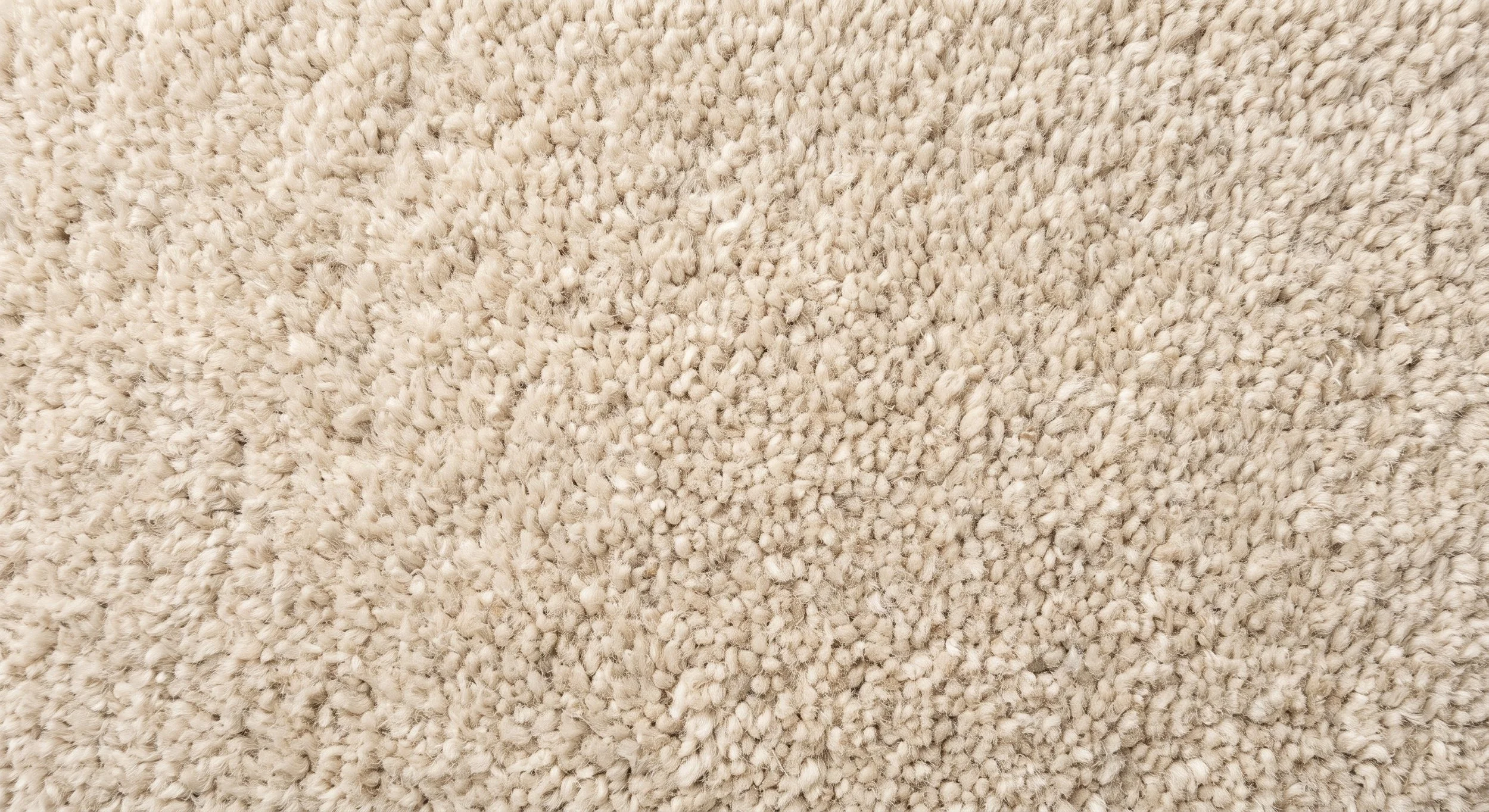 Close-up of a light beige carpet with a plush, textured surface.