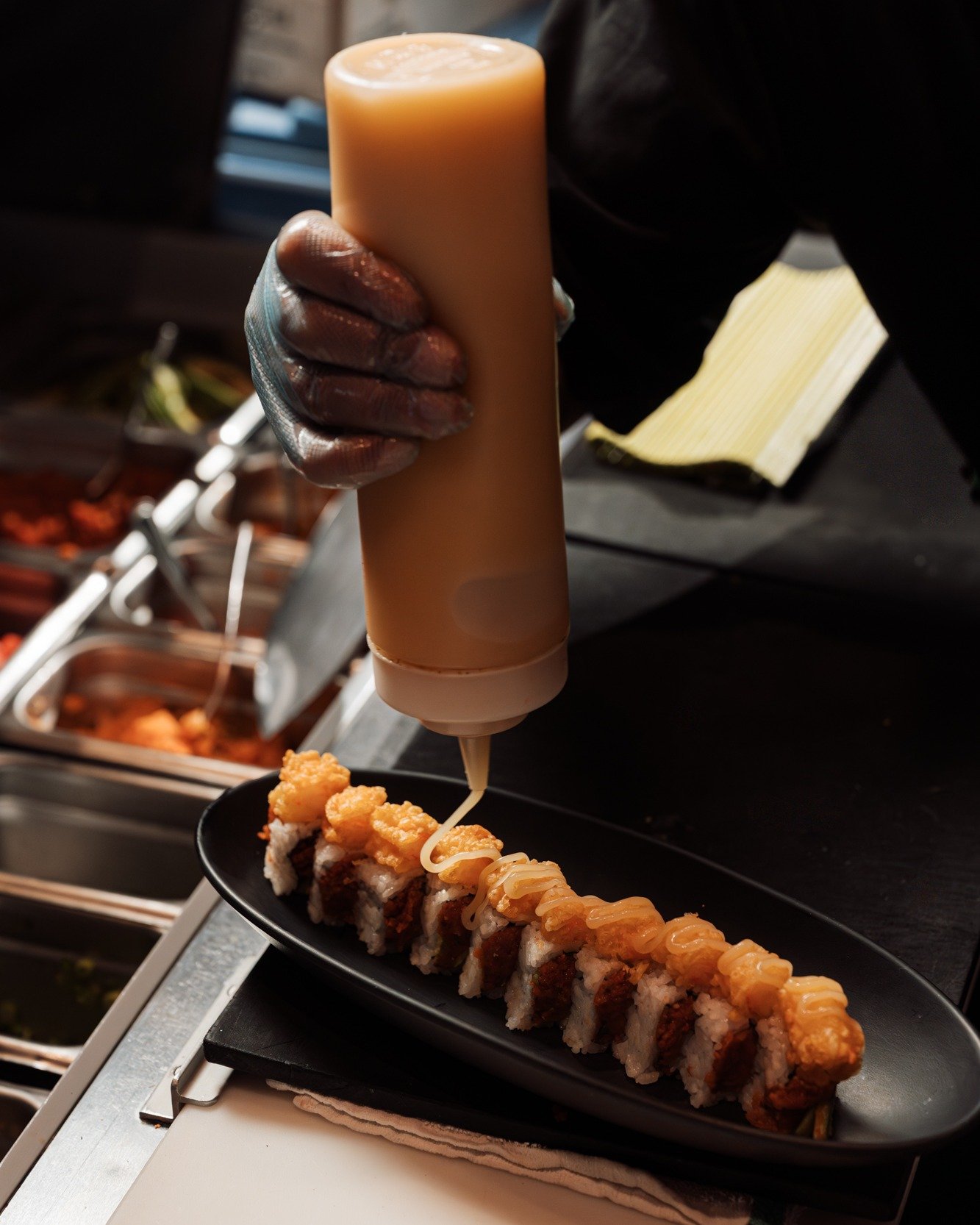 The final drizzle: local white truffle honey aioli on the Bumble Crunch!🍣🍯🐝 Stop by, we're open!