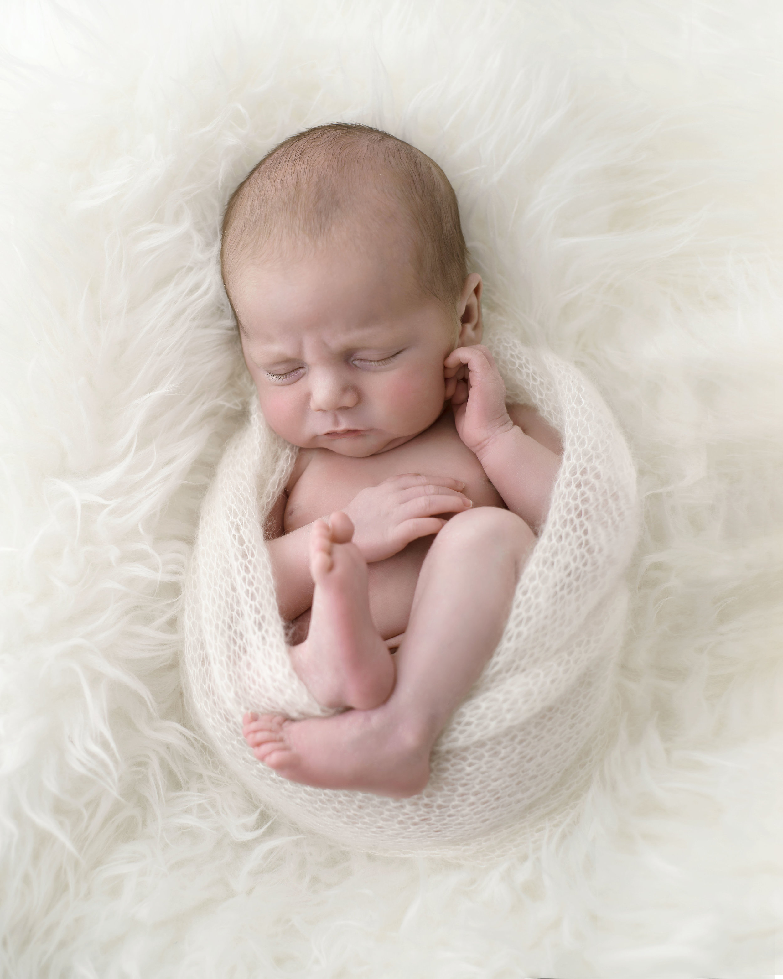 newborn wrapped in white knit sleeping softly