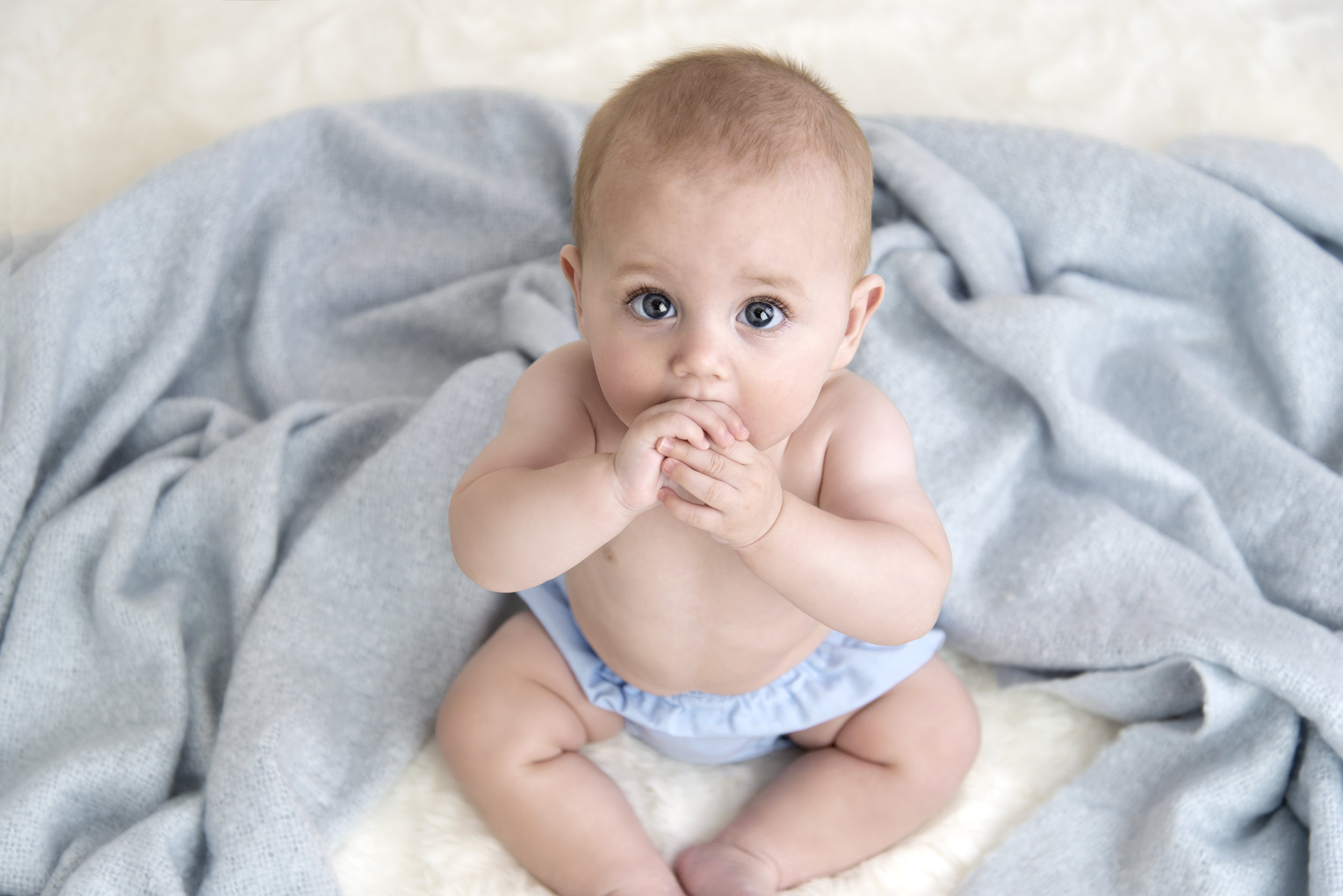 baby boy sitting on blue blanket with beautiful eyes