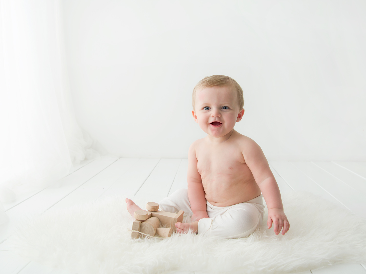 simple white background baby boy with wooden toys