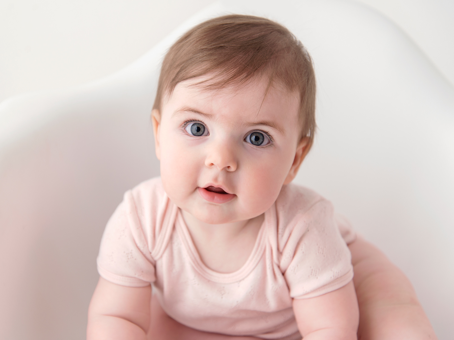 baby girl wearing pink vest with rosy cheeks