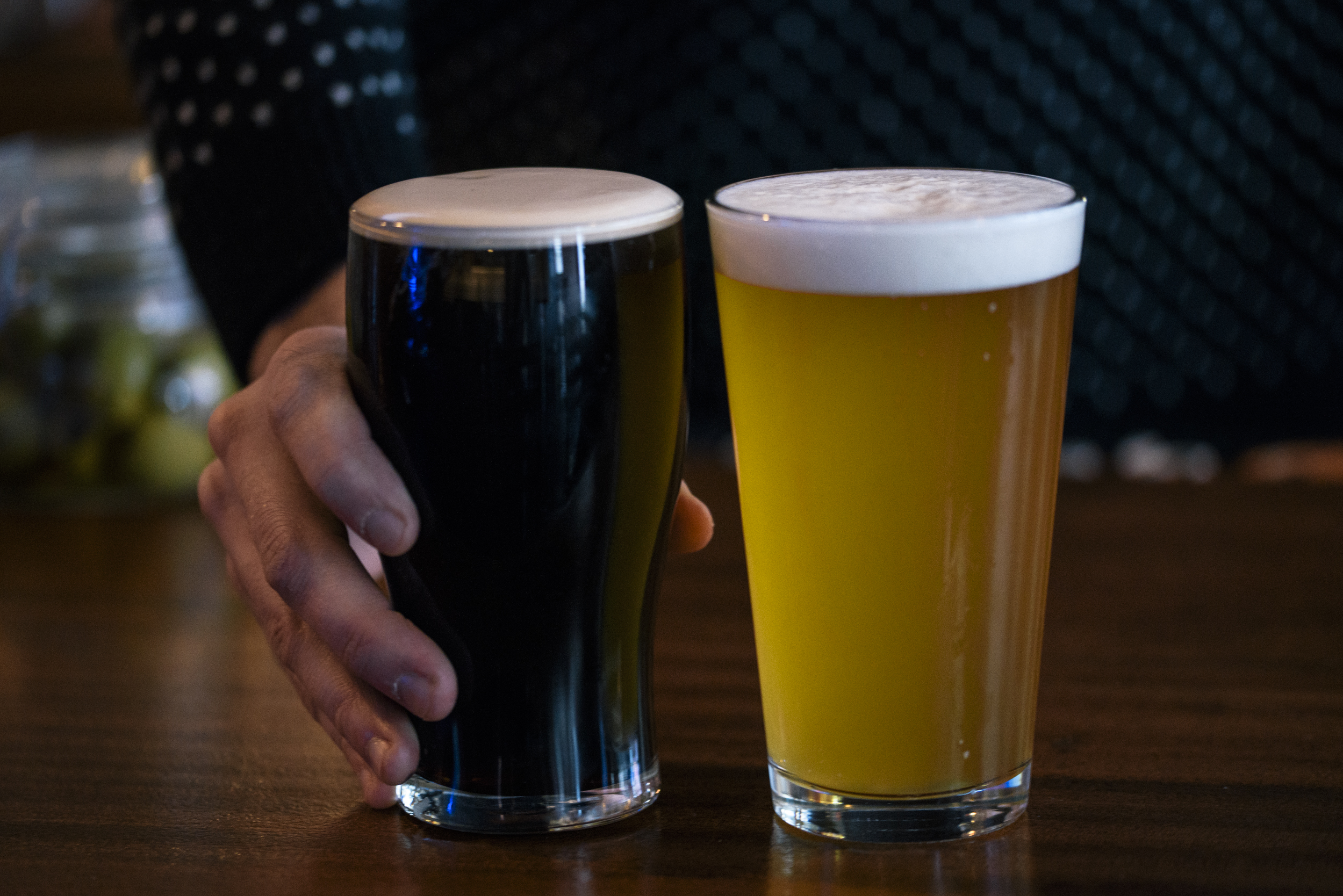 two pints of draft beer in pint glasses, one dark beer and one light beer