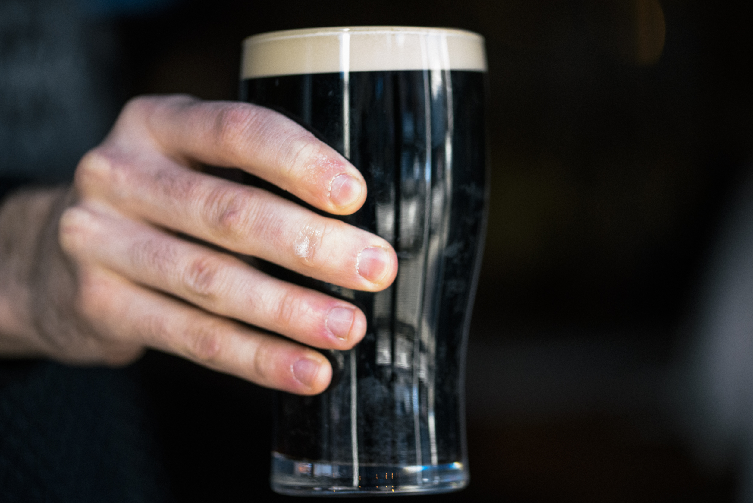hand holding up pint of guinness beer
