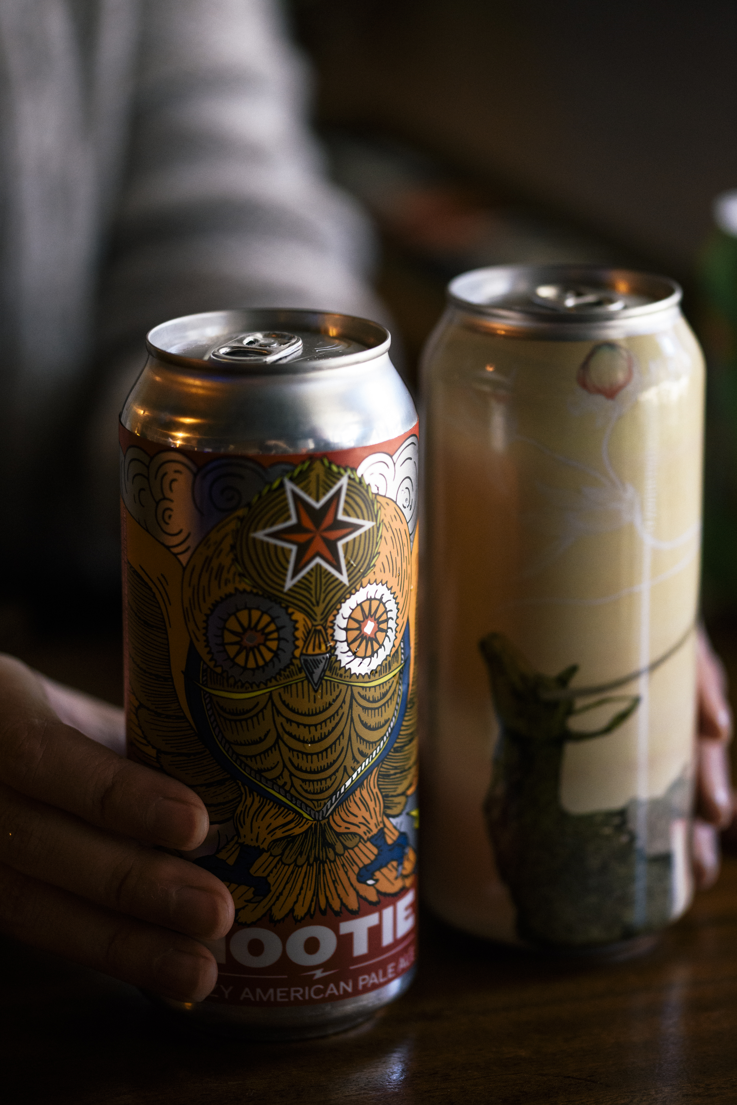 close up of bartender hands with two cans of beer