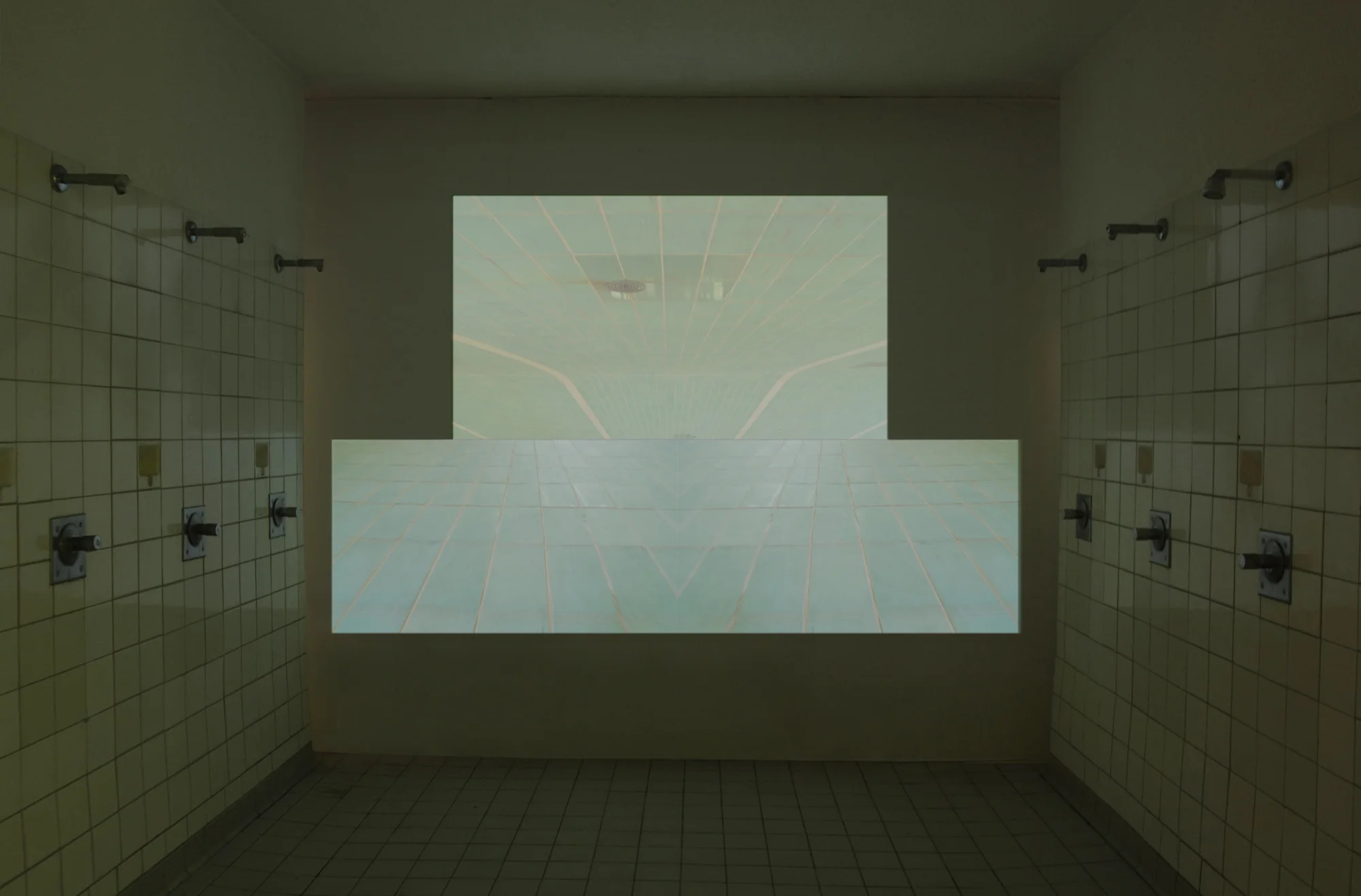 kacheln, three-channel video projection, 6:09 min., 2011 (installation view) In kacheln the camera speeds over the tiled floor of an empty swimming pool. It moves at different angles and perspectives making the tile pattern appear like a perspective grid, merging it into one dragging surface, as well as fragmenting it with a kaleidoscopic effect to create new spatial situations. The camera explores the swimming pool following the three tracks and the limiting lines that before determined the movement of the swimmers.