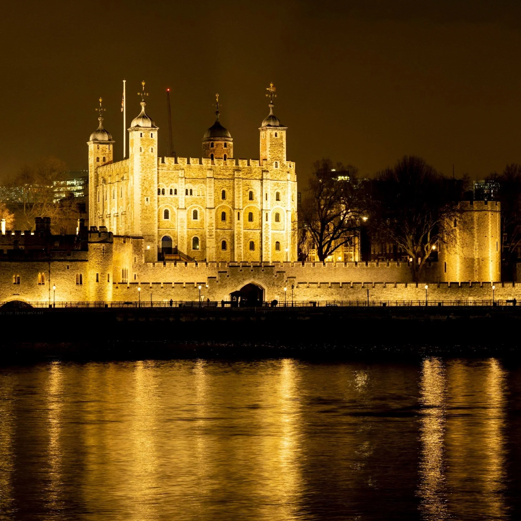 London Castle illuminated at night with reflections on the river.