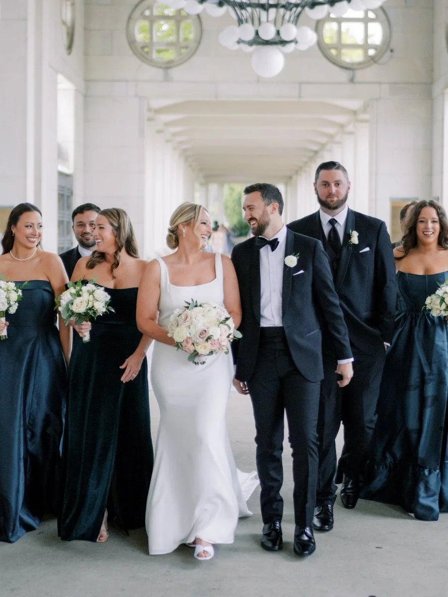 Wedding party walking in teal dresses holding blush and white rose bouquets in St. Louis.