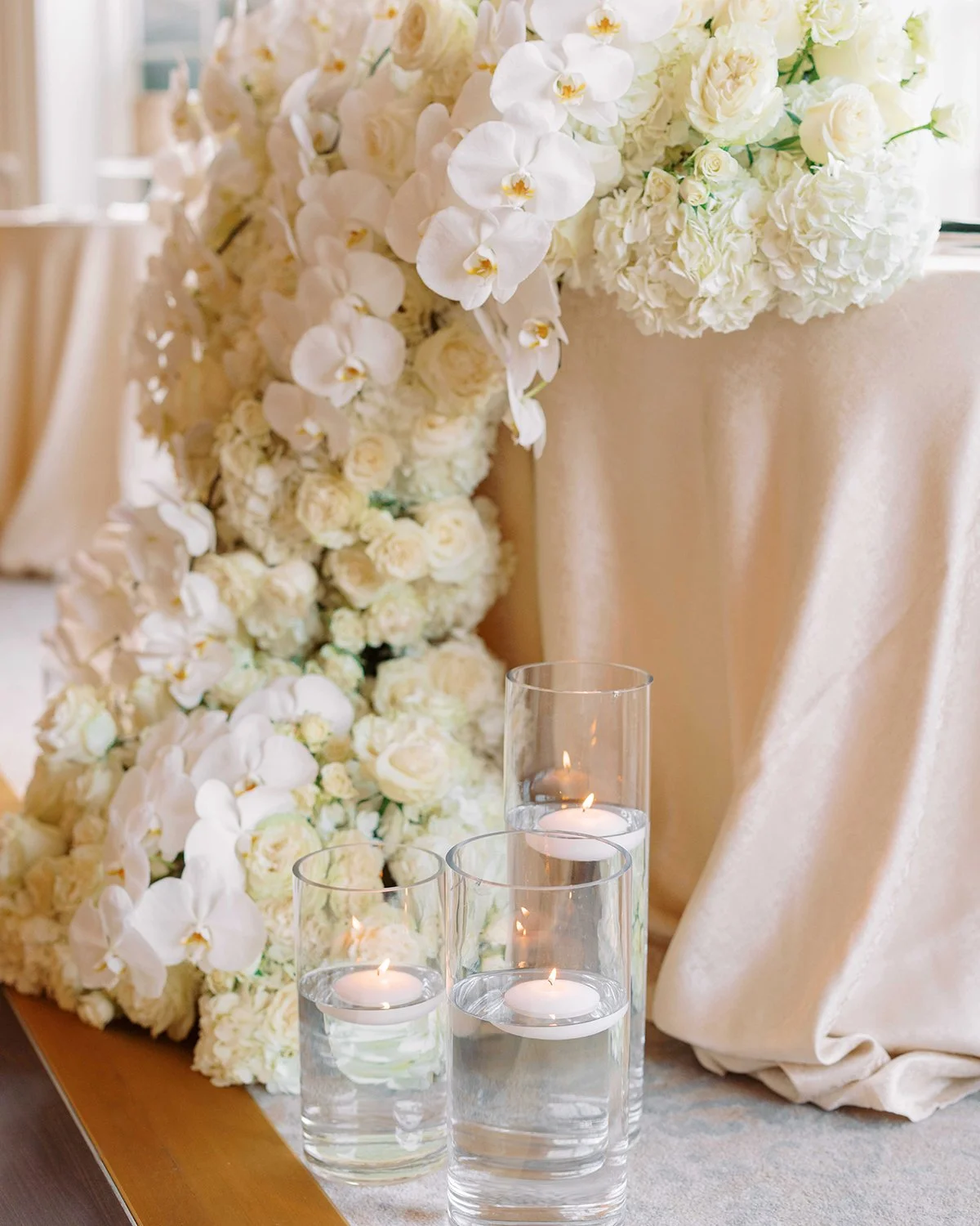 Lush, cascading floral table flowers will always have a certain swoon factor! 🥰

White orchids, roses, and hydrangea everywhere, spilling right off the table and onto the floor like a floral waterfall.

The gold accents, the candlelight, the all-whi
