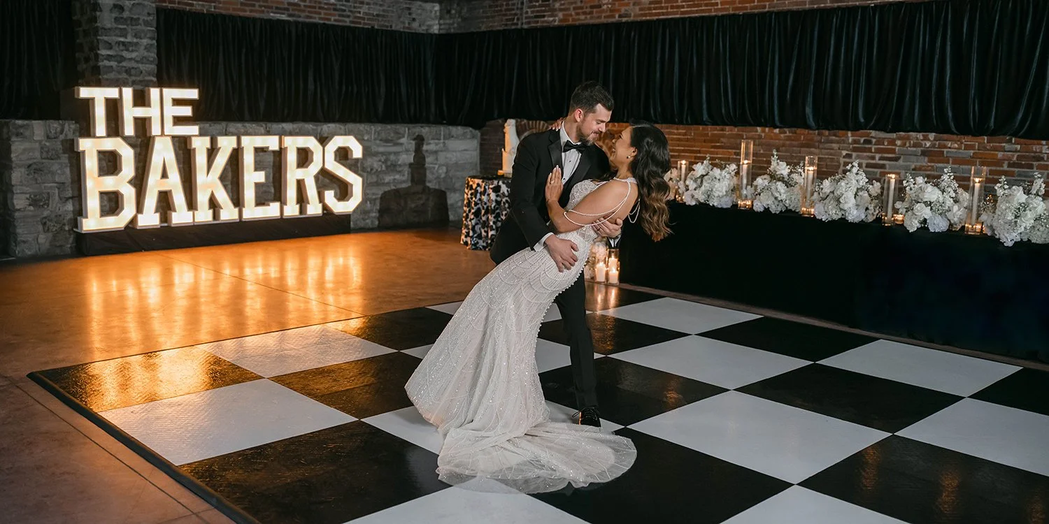 Bride and groom first dance on a checkered dance floor surrounded by white wedding flowers at Gatsby Events in St. Louis.
