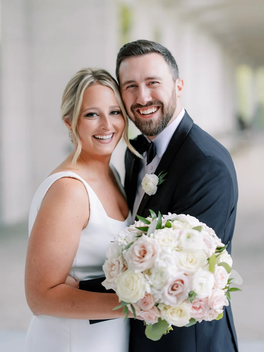 Bride and groom holding blush and white rose bouquet inin St. Louis.