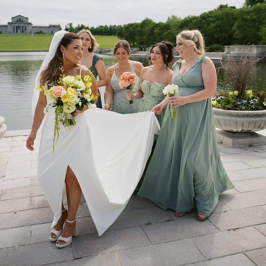 Bride and bridesmaids walking in front of the St. Louis Art Museum with wedding bouquets designed by Belli Fiori.