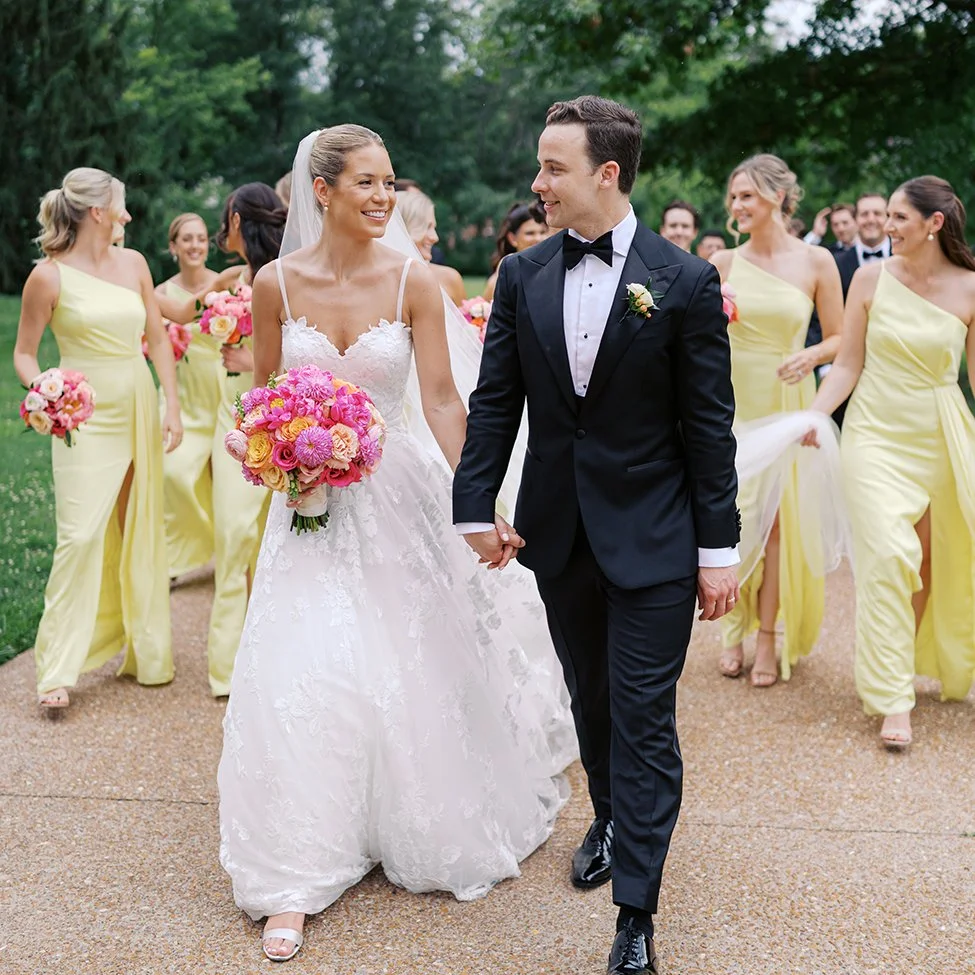 Bride and groom walking with bridesmaids in yellow dresses in St. Louis.