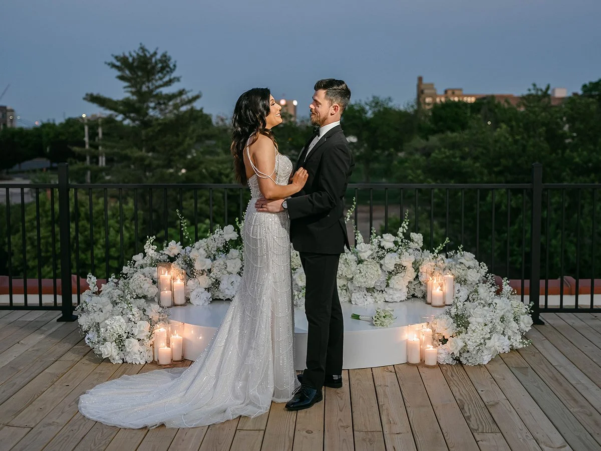 Bride and groom surrounded by white wedding flowers on the rooftop of the Gatsby Events in St. Louis.