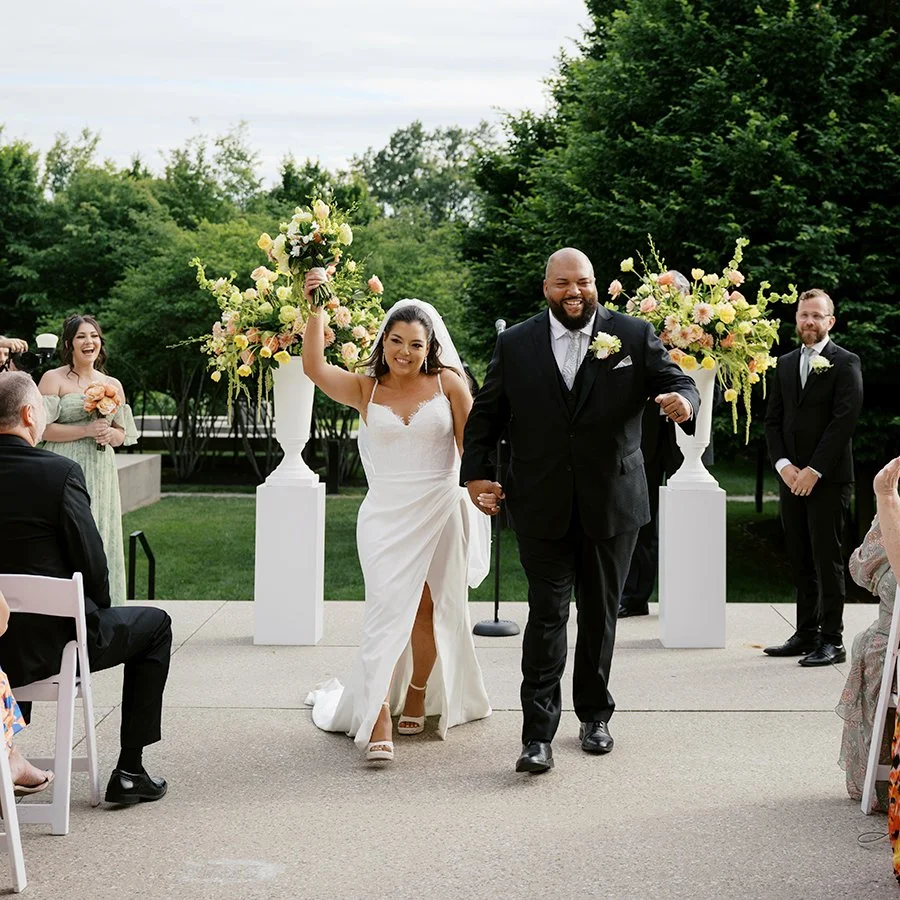 Bride and groom walking up their outdoor wedding ceremony aisle at the St. Louis Art Museum designed by Belli Fiori.