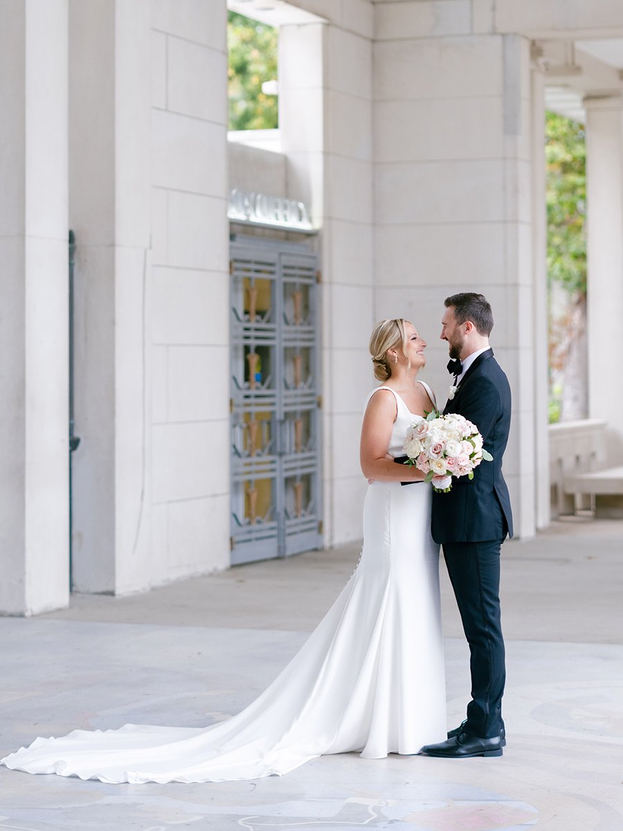 Bride and groom holding blush and white rose bouquet inin St. Louis.