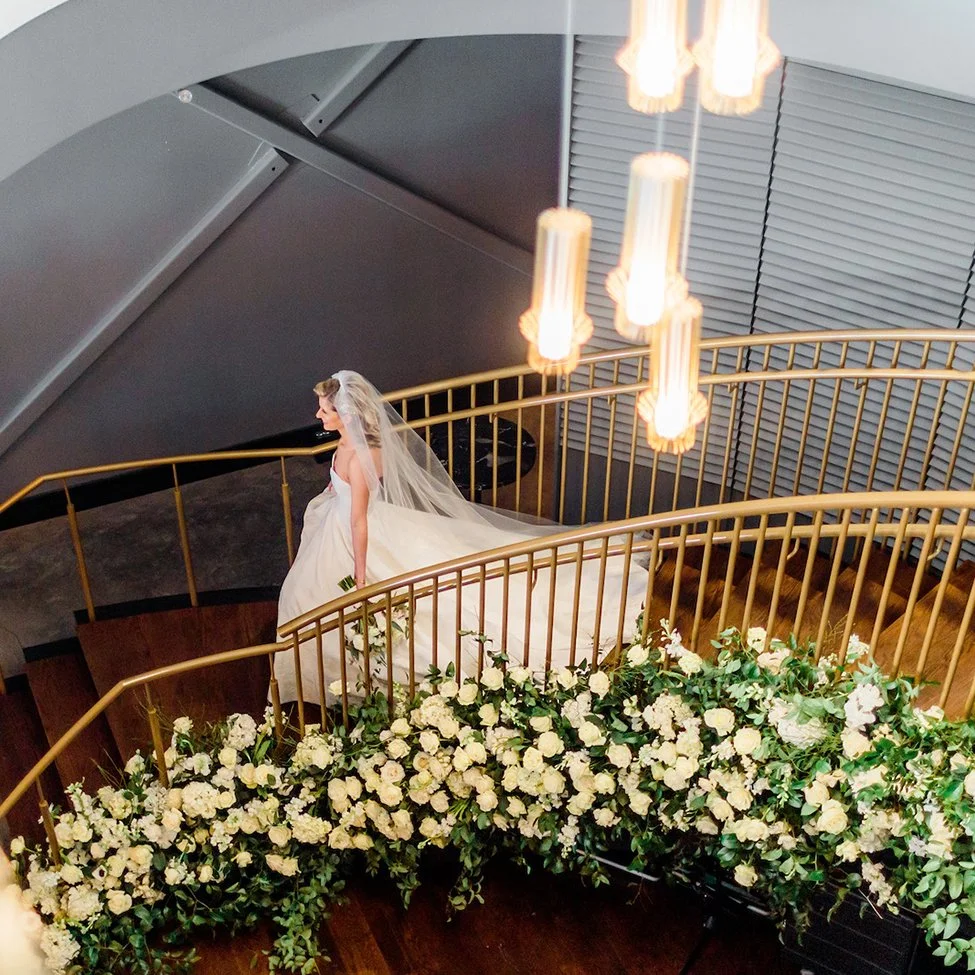 Bride going down a floral covered staircase at The Dogwood venue in St. Louis, Missouri.