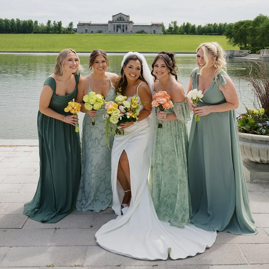 Bride and bridesmaids walking in front of the St. Louis Art Museum with wedding bouquets designed by Belli Fiori.