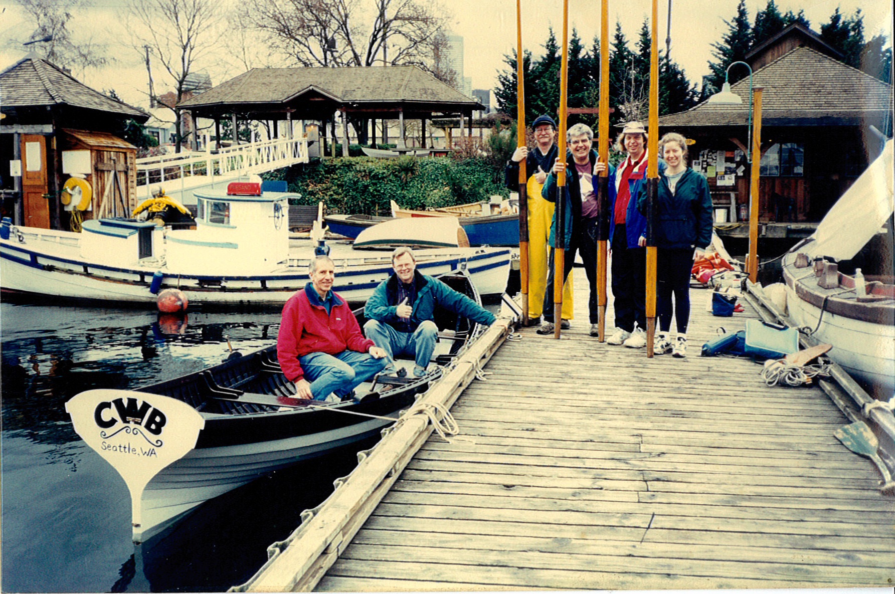 Volunteers standing on the dock holding large sweeps