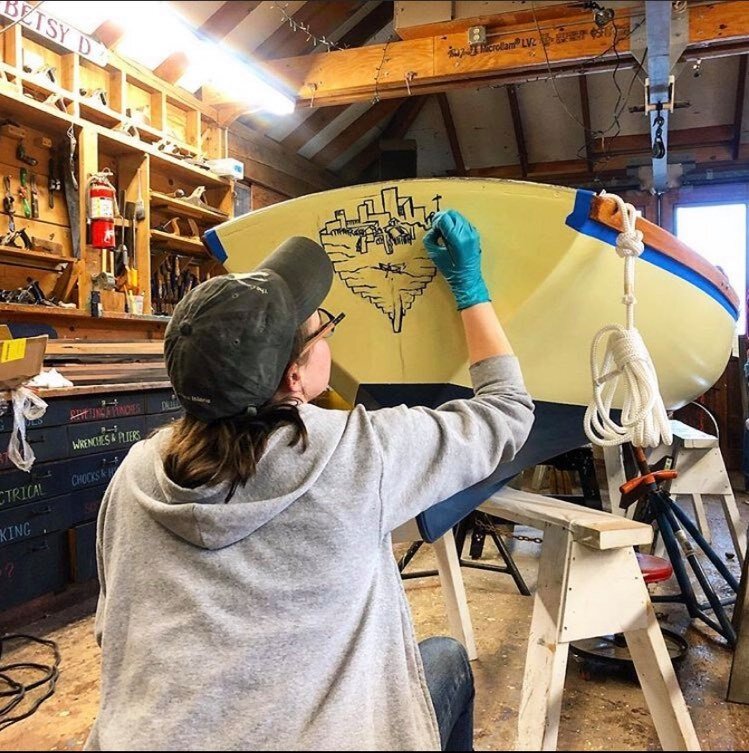 Shleby Allman paints art on the transom of a rowboat