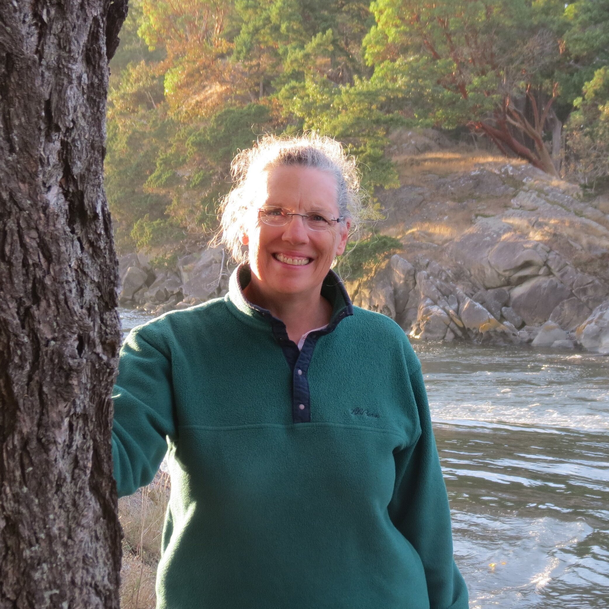 Nancy Engel stands by a tree in front of a river