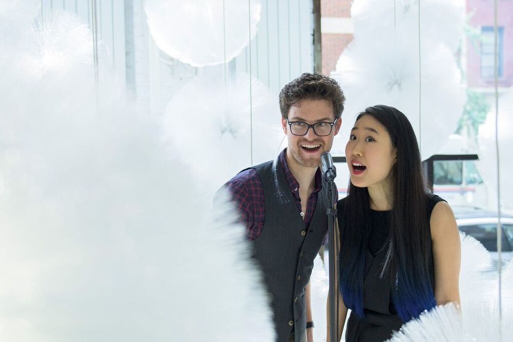 NEW INC members singing into microphone